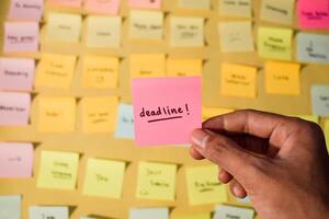 Hand hold sticky notes with words Deadline. Motivational words for personal development, inspirational handwriting. Sticky notes background photo