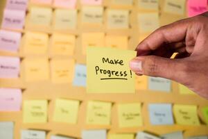 Hand hold sticky notes with words Make Progress. Motivational words for personal development, inspirational handwriting. Sticky notes background photo