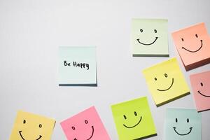 Be Happy and smile emoticon on sticky notes. Motivational words for personal development, inspirational handwriting. Isolated on background photo