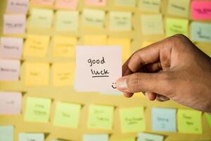 Hand hold sticky notes with words Good Luck. Motivational words for personal development, inspirational handwriting. Sticky notes background photo
