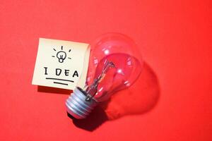 Idea on sticky notes and lightbulb. Isolated red background and copy space photo