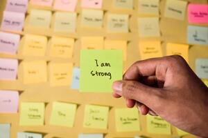 Hand hold sticky notes with words I am strong, Motivational personal development, inspirational handwriting. Sticky notes background photo