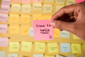 Hand hold sticky notes with words Time to Smile. Motivational words for personal development, inspirational handwriting. Sticky notes background photo
