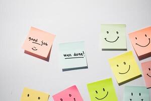 Good Job and well done with smile emoticon on sticky notes. Motivational words for personal development, inspirational handwriting. Isolated on background photo