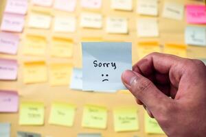 Hand hold sticky notes with words sorry, Motivational word for personal development, inspirational handwriting. Sticky note background photo