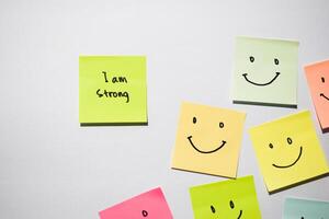 I am strong and smile emoticon on sticky notes. Motivational for personal development, inspirational handwriting. Isolated on background photo