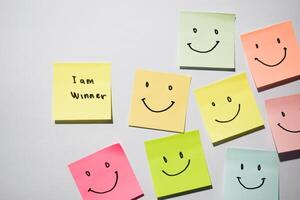 I am winner and smile emoticon on sticky notes. Motivational words for personal development, inspirational handwriting. Isolated on background photo