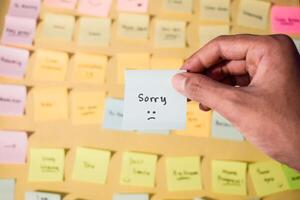 Hand hold sticky notes with words sorry, Motivational word for personal development, inspirational handwriting. Sticky note background photo