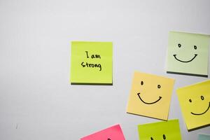 I am strong and smile emoticon on sticky notes. Motivational words for personal development, inspirational handwriting. Isolated on background photo