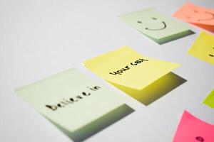 Believe in yourself and smile emoticon on sticky notes. Motivational for personal development, inspirational handwriting. Isolated on background photo