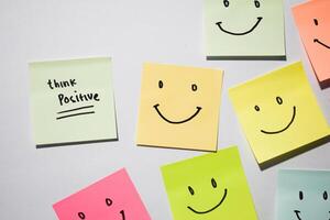 Think Positive and smile emoticon on sticky notes. Motivational words for personal development, inspirational handwriting. Isolated on background photo