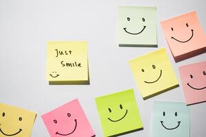 Just Smile and smile emoticon on sticky notes. Motivational words for personal development, inspirational handwriting. Isolated on background photo