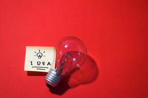 idea en pegajoso notas y bombilla. aislado rojo antecedentes y Copiar espacio foto
