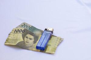 indonesia 4 september 2024, 2000 rupiah banknotes 1000 rupiah banknotes and a blue lighter photographed close up from a side angle with an isolated background photo