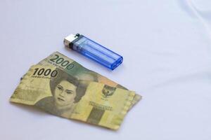 indonesia 4 september 2024, 2000 rupiah banknotes 1000 rupiah banknotes and a blue lighter photographed close up from a side angle with an isolated background photo