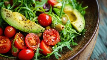 A bowl of salad with tomatoes, avocado and olives photo