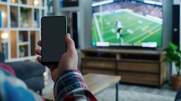 Watching American Football Game on TV with Smartphone in Hand, Modern Living Room Interior, Sports Enthusiast Enjoying Live Match, Home Entertainment Setup photo
