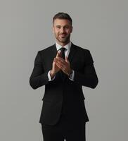 Professional Businessman Clapping in Black Suit on Isolated Gray Background - Confident and Successful Corporate Executive photo