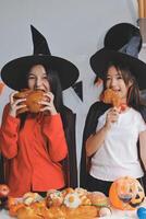 friendship, holiday and people concept - group of happy smiling friends in halloween costumes of vampire, devil, witch and cheetah at home party photo