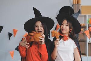 friendship, holiday and people concept - group of happy smiling friends in halloween costumes of vampire, devil, witch and cheetah at home party photo