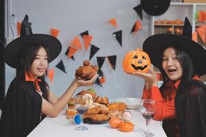 friendship, holiday and people concept - group of happy smiling friends in halloween costumes of vampire, devil, witch and cheetah at home party photo