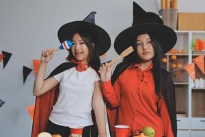 friendship, holiday and people concept - group of happy smiling friends in halloween costumes of vampire, devil, witch and cheetah at home party photo