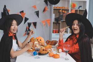 friendship, holiday and people concept - group of happy smiling friends in halloween costumes of vampire, devil, witch and cheetah at home party photo