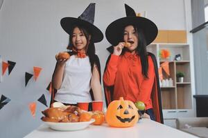friendship, holiday and people concept - group of happy smiling friends in halloween costumes of vampire, devil, witch and cheetah at home party photo