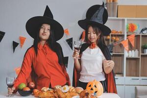 friendship, holiday and people concept - group of happy smiling friends in halloween costumes of vampire, devil, witch and cheetah at home party photo