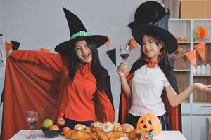 friendship, holiday and people concept - group of happy smiling friends in halloween costumes of vampire, devil, witch and cheetah at home party photo