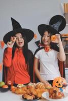 friendship, holiday and people concept - group of happy smiling friends in halloween costumes of vampire, devil, witch and cheetah at home party photo