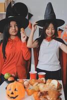 friendship, holiday and people concept - group of happy smiling friends in halloween costumes of vampire, devil, witch and cheetah at home party photo