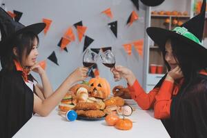 friendship, holiday and people concept - group of happy smiling friends in halloween costumes of vampire, devil, witch and cheetah at home party photo