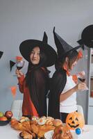 friendship, holiday and people concept - group of happy smiling friends in halloween costumes of vampire, devil, witch and cheetah at home party photo