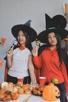 friendship, holiday and people concept - group of happy smiling friends in halloween costumes of vampire, devil, witch and cheetah at home party photo