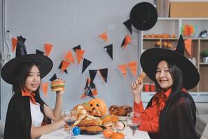 friendship, holiday and people concept - group of happy smiling friends in halloween costumes of vampire, devil, witch and cheetah at home party photo