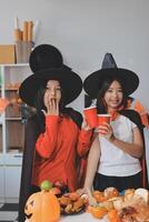 friendship, holiday and people concept - group of happy smiling friends in halloween costumes of vampire, devil, witch and cheetah at home party photo
