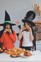 friendship, holiday and people concept - group of happy smiling friends in halloween costumes of vampire, devil, witch and cheetah at home party photo