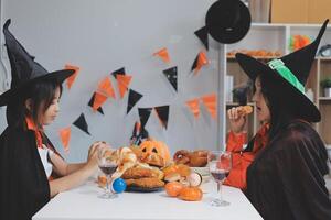 friendship, holiday and people concept - group of happy smiling friends in halloween costumes of vampire, devil, witch and cheetah at home party photo