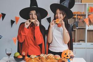 friendship, holiday and people concept - group of happy smiling friends in halloween costumes of vampire, devil, witch and cheetah at home party photo