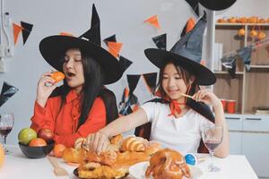 friendship, holiday and people concept - group of happy smiling friends in halloween costumes of vampire, devil, witch and cheetah at home party photo
