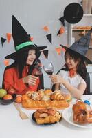 friendship, holiday and people concept - group of happy smiling friends in halloween costumes of vampire, devil, witch and cheetah at home party photo