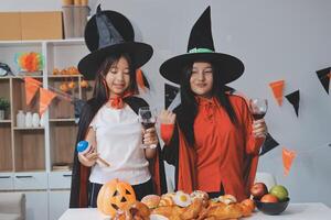 friendship, holiday and people concept - group of happy smiling friends in halloween costumes of vampire, devil, witch and cheetah at home party photo