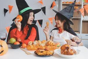 friendship, holiday and people concept - group of happy smiling friends in halloween costumes of vampire, devil, witch and cheetah at home party photo