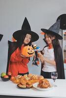 friendship, holiday and people concept - group of happy smiling friends in halloween costumes of vampire, devil, witch and cheetah at home party photo