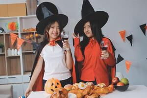 friendship, holiday and people concept - group of happy smiling friends in halloween costumes of vampire, devil, witch and cheetah at home party photo