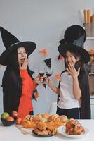 friendship, holiday and people concept - group of happy smiling friends in halloween costumes of vampire, devil, witch and cheetah at home party photo