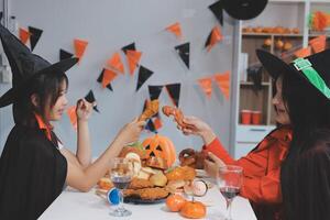 friendship, holiday and people concept - group of happy smiling friends in halloween costumes of vampire, devil, witch and cheetah at home party photo
