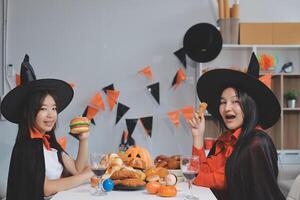 friendship, holiday and people concept - group of happy smiling friends in halloween costumes of vampire, devil, witch and cheetah at home party photo
