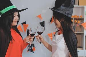friendship, holiday and people concept - group of happy smiling friends in halloween costumes of vampire, devil, witch and cheetah at home party photo